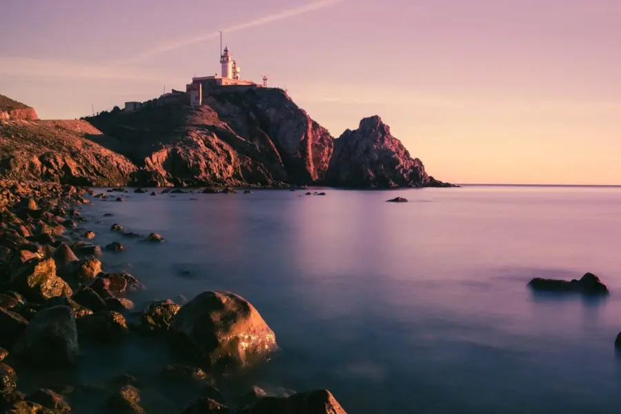 Costa rocosa con faro al atardecer