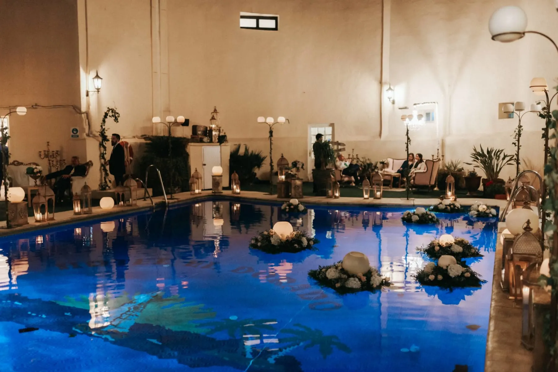 Piscina iluminada de noche con velas durante una celebración