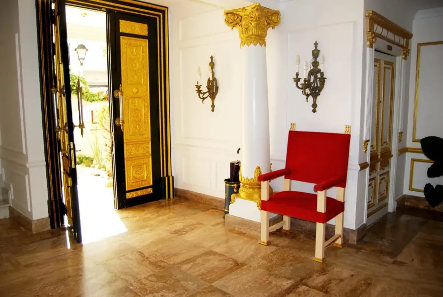 Sillón rojo de estilo palaciego junto a una puerta